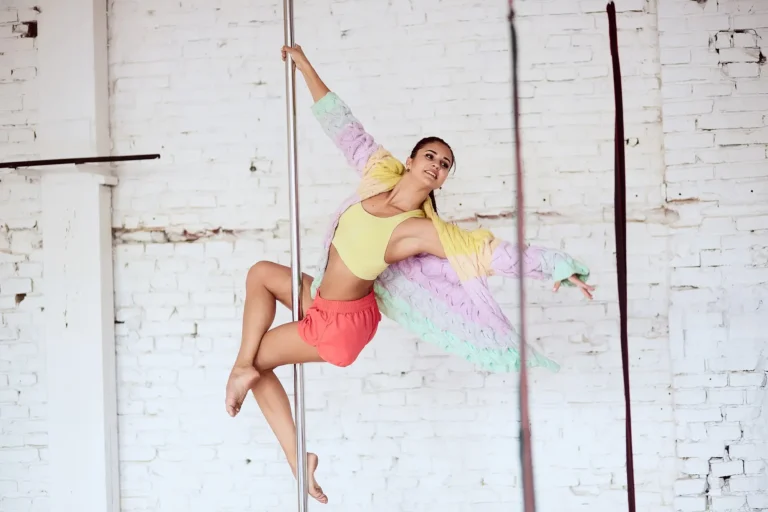 Une femme pratique la pole dance - une danseuse de pole dance exécutant une figure de pole dance dans un studio de pole dance